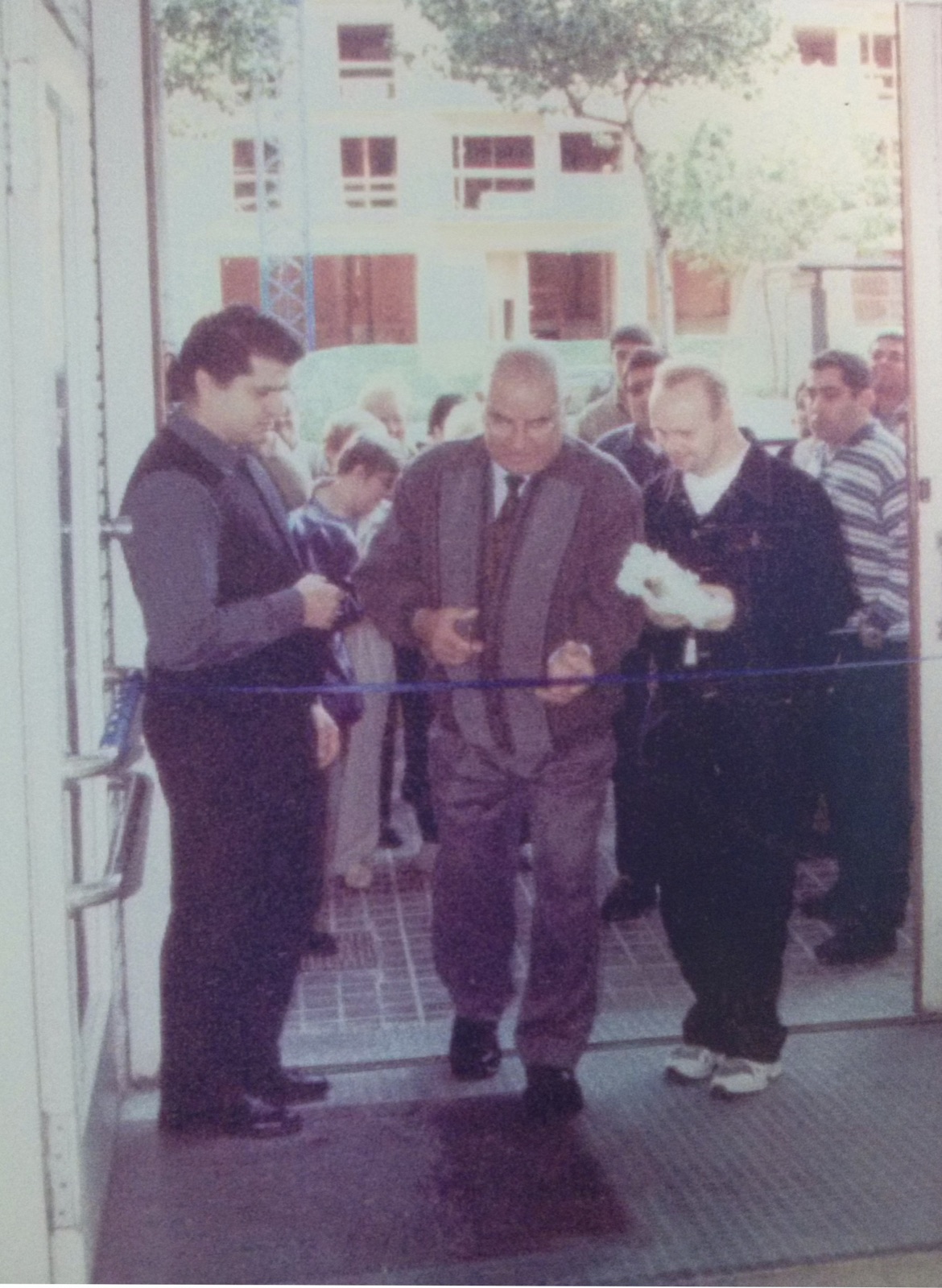 Foto antiga de la inauguració del local, tallant la cinta a la porta