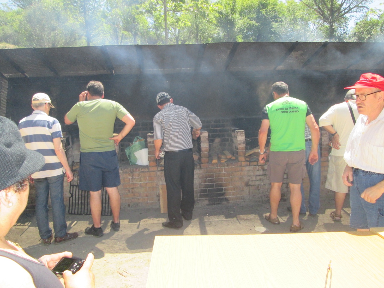 Participants al voltant de la graella d'una barbacoa a l'aire lliure